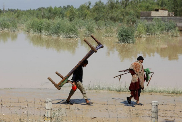 men walk with their belongings along flood waters following rains and floods during the monsoon season in charsadda august 28 2022 photo reuters men walk with their belongings along flood waters following rains and floods during the monsoon season in charsadda august 28 2022 photo reuters