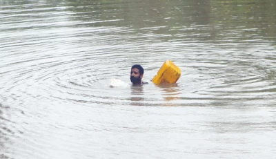 a farmer swims while using an empty canister through a flooded area near qasim bela village on the outskirts of multan photo reuters
