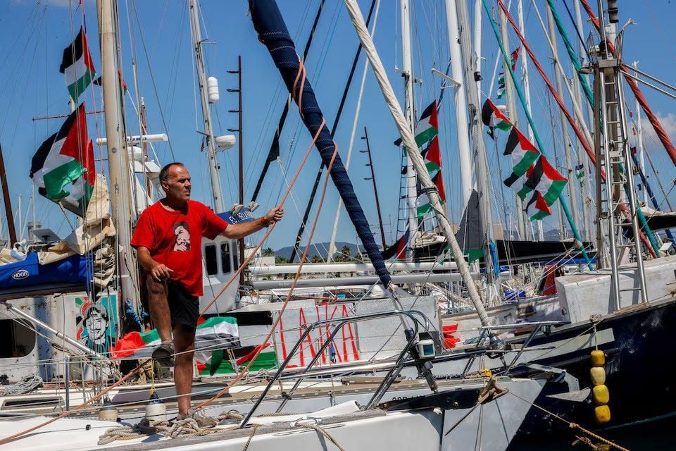 An activist stands on a sailboat from the Global Sumud Flotilla humanitarian expedition as it prepares to set sail for Gaza at the port of Barcelona, Spain, August 30, 2025.PHOTO: REUTERS