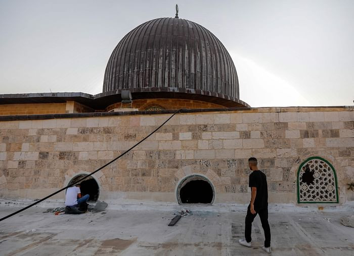 Palestinian youths look into the Al-Aqsa mosque on the first day of the Eidul Azha feast celebrated by Muslims worldwide, on July 20, 2021, through windows which were shattered two days earlier in renewed clashes between Palestinians and Israeli police at the Al-Aqsa complex in Jerusalems old city. PHOTO: AFP