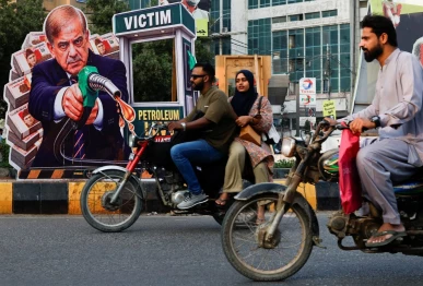 people on motorbikes ride past a portrait of pakistani prime minister shehbaz sharif set up in protest against rising fuel prices amid the u s  iran conflict ahead of the nationwide rollout of a government scheme offering a rs100 per litre subsidy to eligible motorcycles rickshaws and vehicles up to 800cc in karachi pakistan september 16 2026 reuters