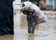a displaced palestinian carries belongings in a flooded tent camp on a rainy day in nuseirat central gaza strip december 12 2025 photo reuters