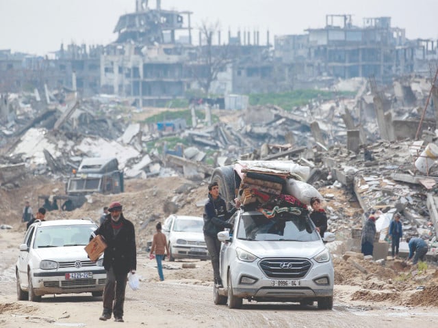 boys ride outside a vehicle loaded with mattresses blankets and a giant cistern moving along a road in the west of beit lahia in the northern gaza strip photo afp