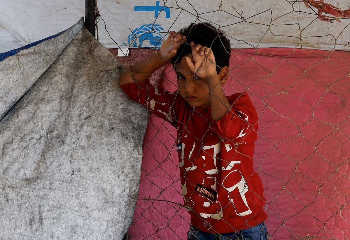 A displaced Palestinian child, who fled Gaza City due to an Israeli military operation, stands by a fence, as he rests on the roadside, in the central Gaza Strip, October 5, 2025. PHOTO: REUTERS