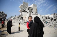 a palestinian woman carries a child as they walk past the rubble of houses destroyed in previous strikes during the israeli military offensive amid the israel hamas conflict in khan younis in the southern gaza strip november 6 2024 photo reuters