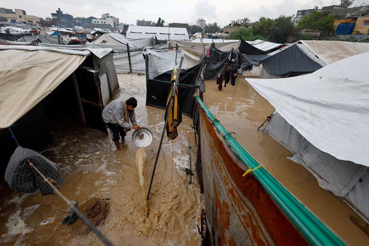 A displaced Palestinian man clears muddy water in a flooded tent camp on a rainy day in Nuseirat, central Gaza Strip, December 12, 2025. PHOTO: REUTERS