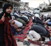 a girl holding a piece of candy stands among palestinians performing morning prayers marking the start of eidul azha on a heavily damaged street in khan yunis in the southern gaza strip on may 27 2026 afp