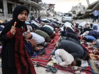 a girl holding a piece of candy stands among palestinians performing morning prayers marking the start of eidul azha on a heavily damaged street in khan yunis in the southern gaza strip on may 27 2026 afp