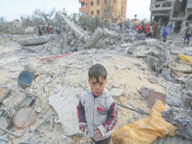 a child looks on as palestinians inspect the site of an israeli strike on a house in khan younis photo reuters