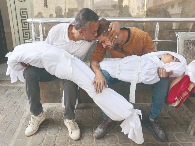 a palestinian man is comforted by a relative as he mourns over the bodies of his children who were killed in overnight israeli strikes at the al shifa hospital in gaza city photo afp