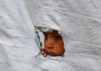 a displaced palestinian boy peers through a tear in a tent wall in gaza city on may 6 2026 photo reuters