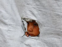 a displaced palestinian boy peers through a tear in a tent wall in gaza city on may 6 2026 photo reuters