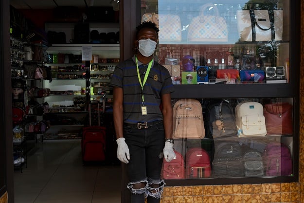 A shop attendant wears gloves and a mask while waiting for customers outside a shop in Windhoek. PHOTO: AFP