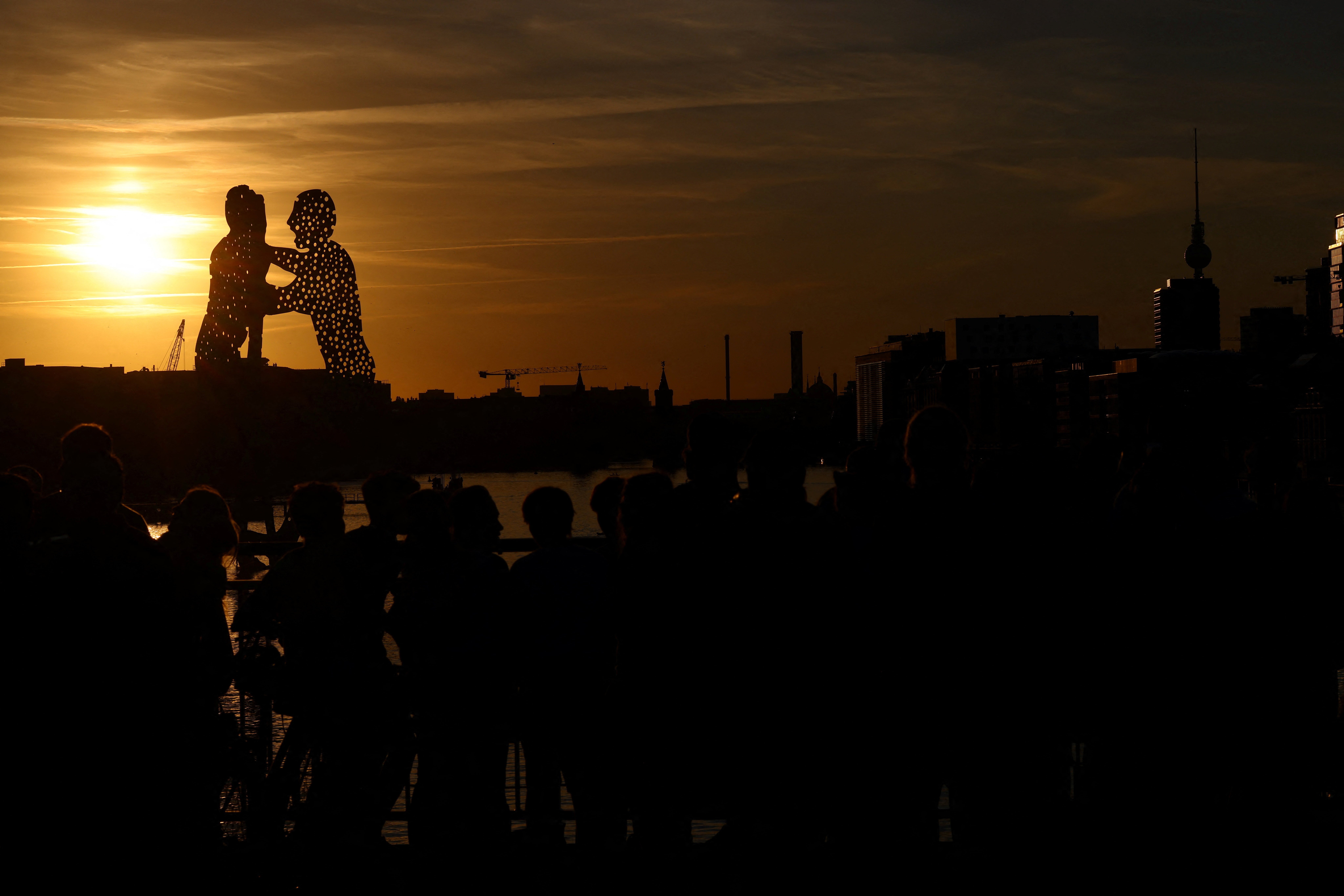 The partial eclipsed sun appears behind the 'Molecule Men', a 30-metre high metal sculpture by Jonathan Borofsky, located in Berlin's Spree river, Germany, August 12, 2026. Photo: Reuters
