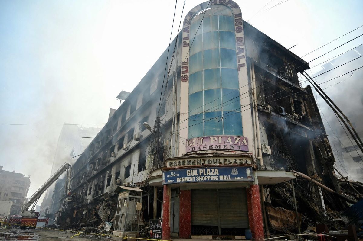 Fire fighters and rescue workers perform a cooling operation amid the debris after a massive fire at a shopping mall in Karachi on January 19, 2026.AFP