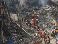 rescue and emergency team members gather near heavy machinery before starting their search for survivors following a massive fire that broke out in the gul plaza shopping mall in karachi on january 22 photo reuters