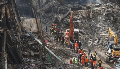 rescue and emergency team members gather near heavy machinery before starting their search for survivors following a massive fire that broke out in the gul plaza shopping mall in karachi on january 22 photo reuters