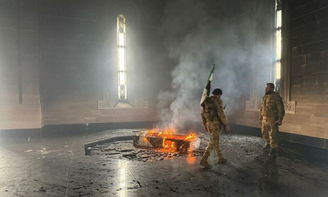 rebel fighters stand next to the burning gravesite of syria s late president hafez al assad at his mausoleum in the family s ancestral village of qardaha in the western latakia province on december 11 2024 after it was stormed by opposition factions photo afp rebel fighters stand next to the burning gravesite of syria s late president hafez al assad at his mausoleum in the family s ancestral village of qardaha in the western latakia province on december 11 2024 after it was stormed by opposition factions photo afp