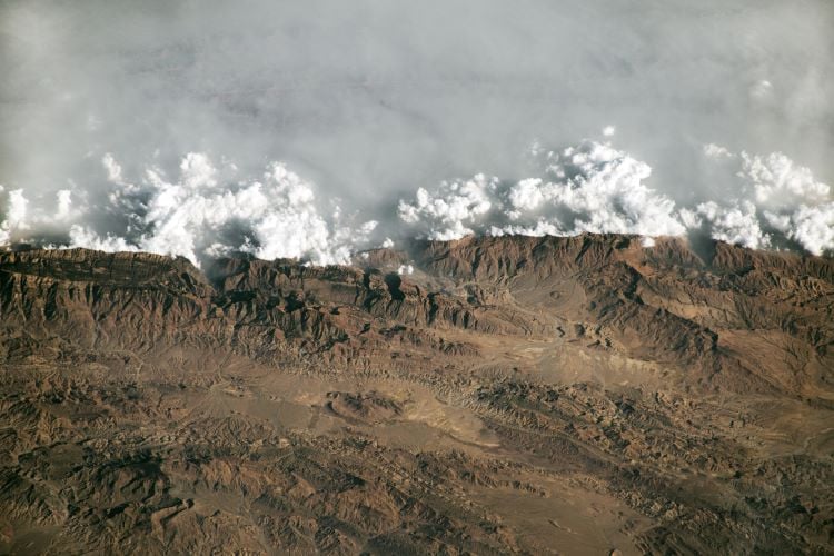 the image showing thick wall of clouds and haze crashing to the peaks of sulaiman mountains in pakistan the phenomenon is called terrain forced flow photo nasa earth observatory iss program