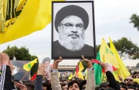 a protester hoists a framed portrait of slain hezbollah leader hassan nasrallah in front of lebanese troops during a riot organized by the terror group outside the airport in beirut lebanon february 15 2025 photo afp