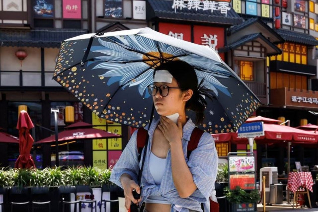 a woman walks with cold patches on her forehead and neck amid a red alert for heatwave in beijing china june 23 2023 photo reuters a woman walks with cold patches on her forehead and neck amid a red alert for heatwave in beijing china june 23 2023 photo reuters