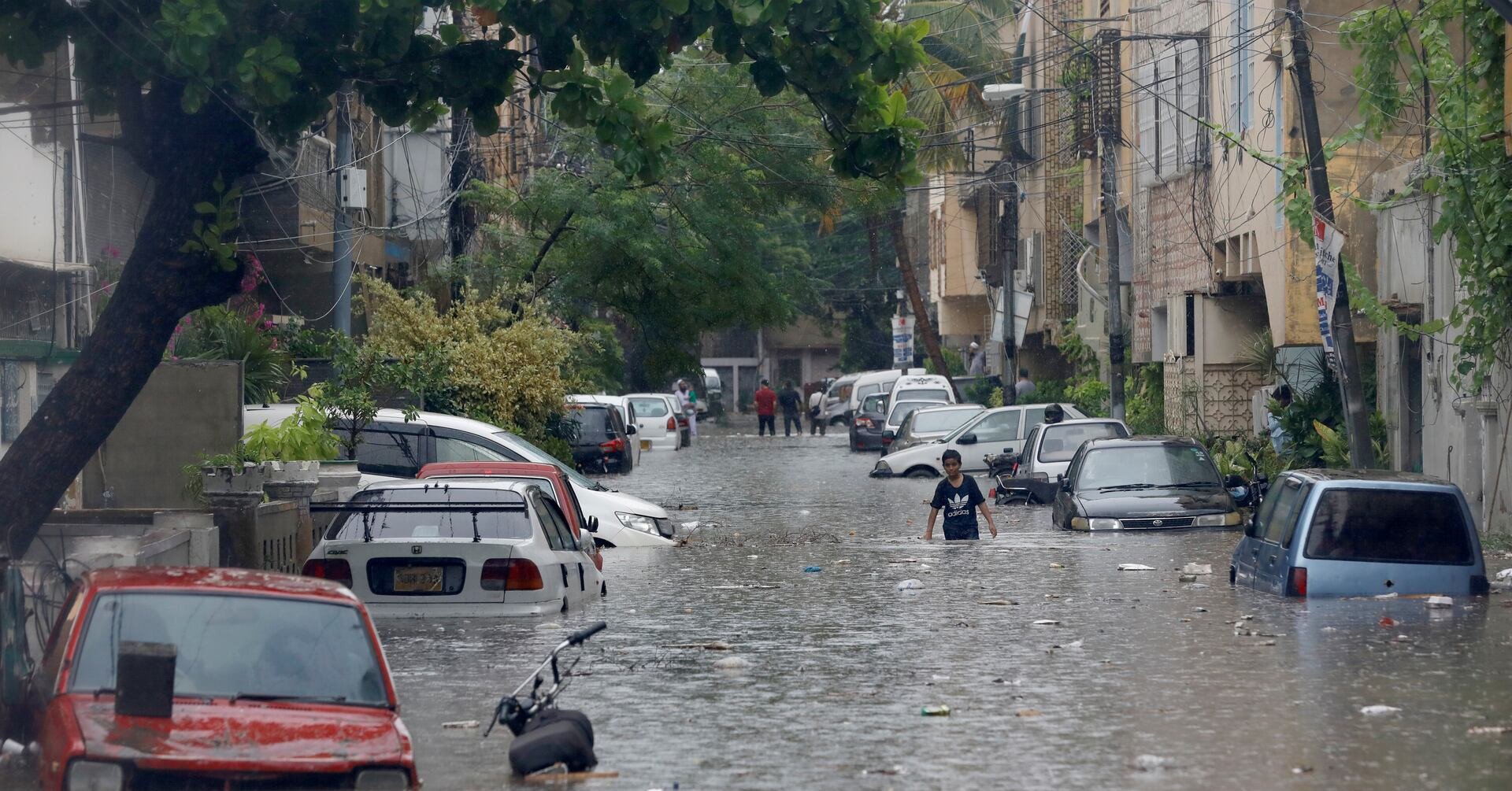 a boy wades through a flooded street with submerged vehicles during the monsoon rain as the outbreak of the coronavirus disease covid 19 continues in karachi pakistan august 25 2020 reuters akhtar soomro