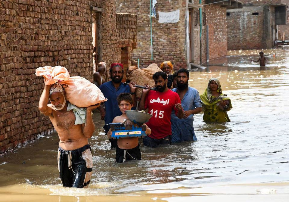 People wade through a flooded street as they carry a woman towards the hospital at Latifabad, Hyderabad, Pakistan, August 22, 2025.PHOTO: REUTERS