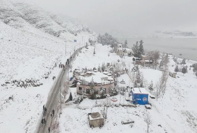fresh snowfall transforms quetta s rugged terrain into a stark winter vista with travellers moving along a snow lined road photo nni