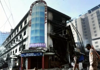 paramilitary personnel walk past charred remains of the gul plaza shopping mall in karachi on jan 22 2026 photo afp