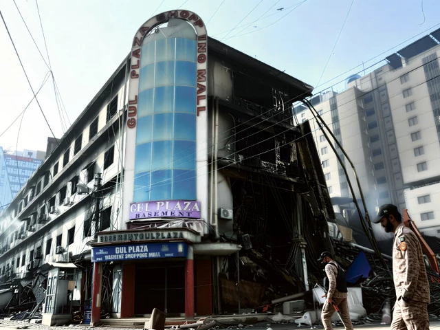 paramilitary personnel walk past charred remains of the gul plaza shopping mall in karachi on jan 22 2026 photo afp paramilitary personnel walk past charred remains of the gul plaza shopping mall in karachi on jan 22 2026 photo afp
