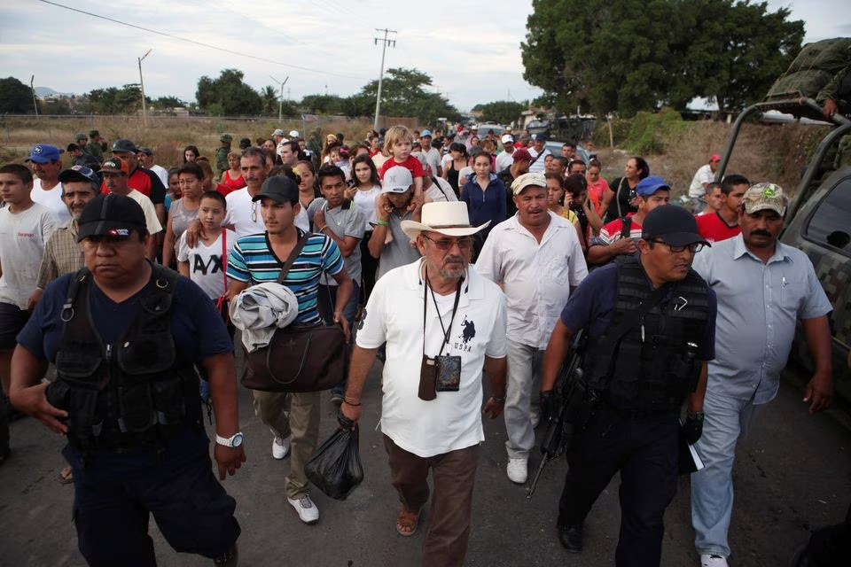 vigilante leader hipolito mora wearing hat c and other vigilantes walk with their family and friends to voluntarily cooperate in a shootout investigation in la ruana michoacan december 27 2014 reuters file photo