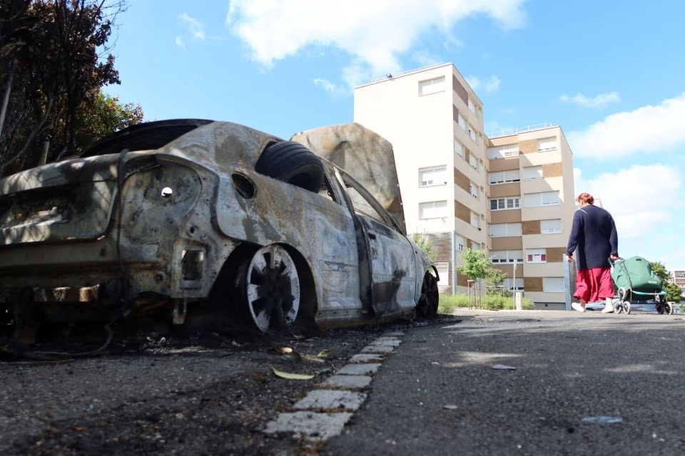 a woman walks past a car burnt during nights of unrest following the death of nahel a 17 year old teenager killed by a french police officer in nanterre during a traffic stop at saint eloy neighbourhood in woippy suburb of the french city of metz france july 5 2023 photo reuters