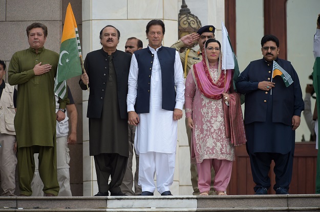 Prime Minister Imran Khan (C) stands with his party leaders as they listen to the national anthem. PHOTO: AFP