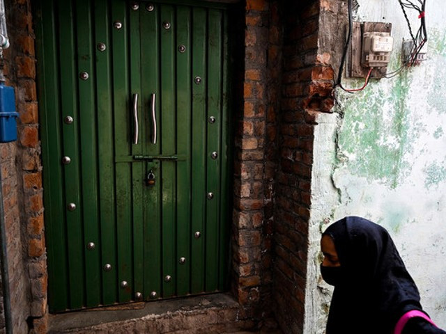 a child walks past a locked house of an attacker who made an assassination attempt on former prime minister imran khan on his container truck a day after at sodhra in gujranwala district on november 4 2022 photo afp