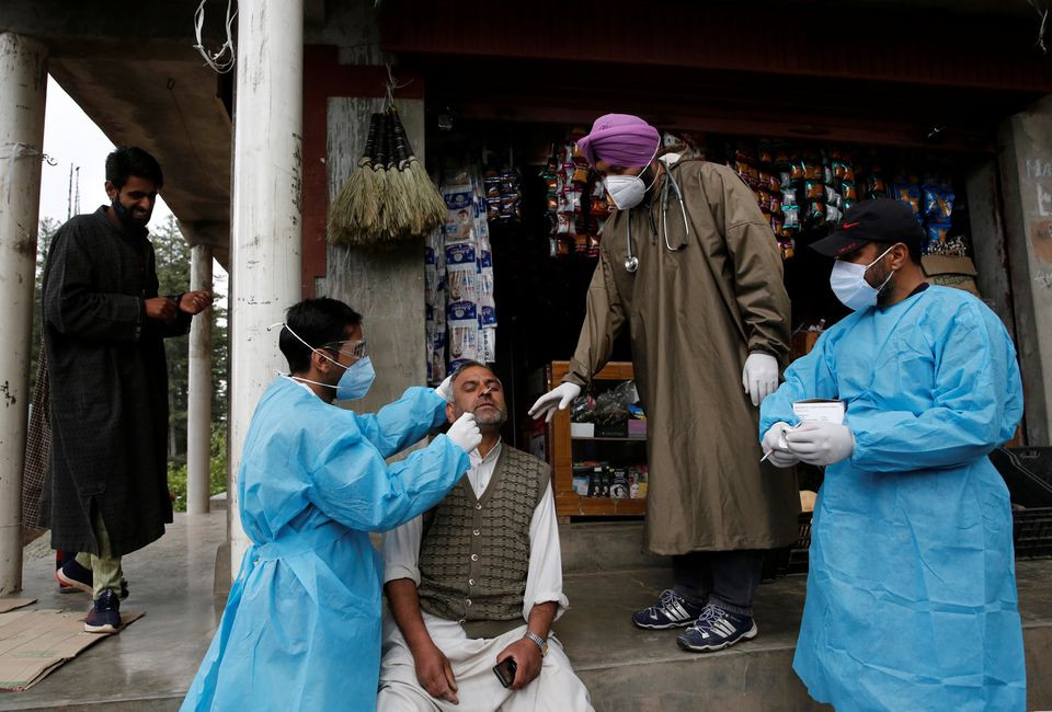 a healthcare worker takes a nasal swab sample from a man for a coronavirus disease covid 19 test in front of a shop in nawroz baba village in central kashmir s budgam district may 20 2021 reuters danish ismail