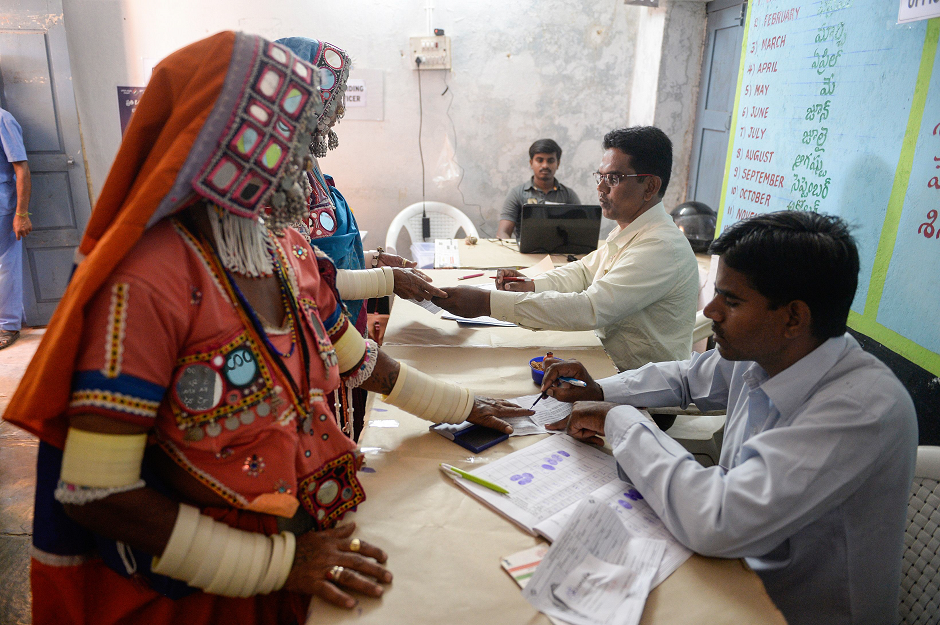 A polling officer marks the finger of Indian lambadi tribeswomen before they vote at a polling station during India's general election at Pedda Shapur village on the outskirts of Hyderabad on April 11, 2019. PHOTO: AFP