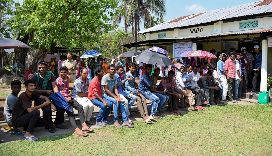 Indian voters sit holding umbrellas to protect themselves from heat as they queue to cast their vote at a polling station at a polling station during India's general election in Salna Tea Estate, some 170 km from Guwahati, the capital city of India s northeastern state of Assam on April 11, 2019. PHOTO: AFP