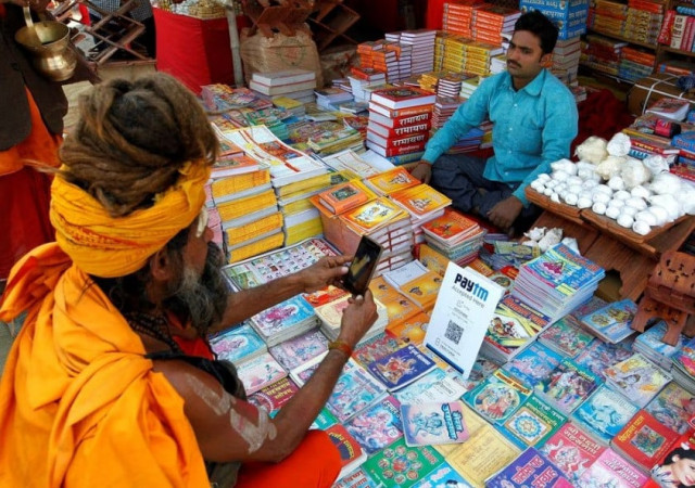 a sadhu or a hindu holy man pays the vendor through paytm a digital wallet company after buying a book during the annual religious festival of magh mela in allahabad india january 26 2017 reuters jitendra prakash