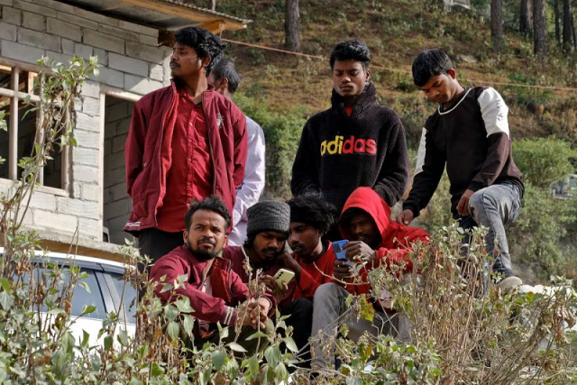 relatives of the trapped workers watch their mobile phones as they wait outside the collapsed tunnel in uttarakhand india november 25 2023 photo reuters