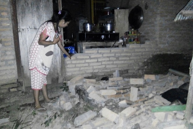 A resident is seen beside the collapsed brick wall of her house at Tobadak village in Central Mamuju, western Sulawesi province, on September 28, 2018. PHOTO: AFP