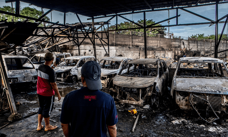 two men look at burnt cars in plumpang north jakarta on march 4 2023 after a fire at a nearby state run fuel storage depot run by energy firm pertamina photo afp