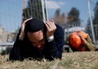 people take cover on the ground as sirens sound near the site of a fatal iranian missile strike on sunday amid the u s  israel conflict with iran in beit shemesh israel march 2 2026 photo reuters