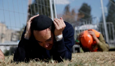 people take cover on the ground as sirens sound near the site of a fatal iranian missile strike on sunday amid the u s  israel conflict with iran in beit shemesh israel march 2 2026 photo reuters