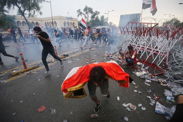 Iraqi protesters run for cover from teargas canisters fired by security forces during an anti-government demonstration on Al-Jumhuriya Bridge in the Iraqi capital Baghdad on October 25, 2019 (Photo: AFP)