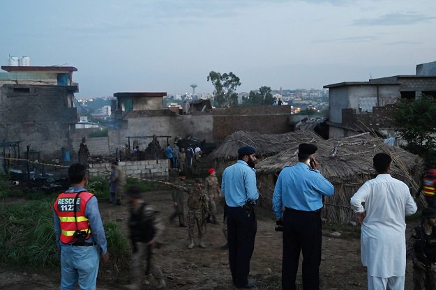 Security officials gather at the scene where a Pakistani Army Aviation Corps aircraft crashed in Rawalpindi. PHOTO: AFP