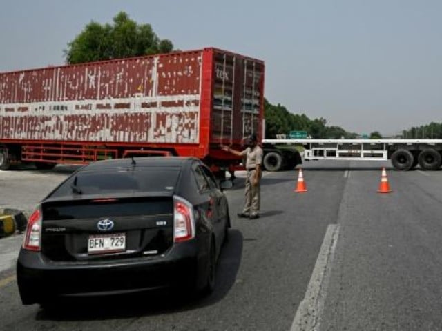 A police officer diverts traffic on the Islamabad–Peshawar Motorway blocked with trucks placed by authorities in Islamabad on September 24, 2026 ahead of opposition party Pakistan Tehreek-e-Insaf (PTI) protest demanding the release of Imran Khan. Photo: AFP