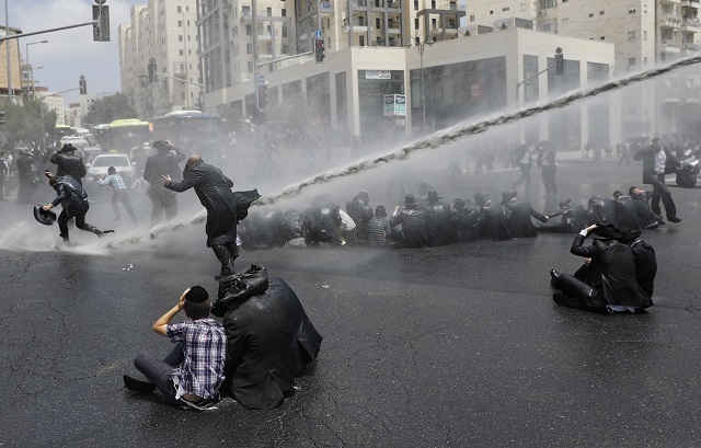 Ultra-Orthodox Jews, demonstrating against the annual Gay Parade, are sprayed with water cannons by Israeli security forces in Jerusalem on August 2, 2018. PHOTO: AFP