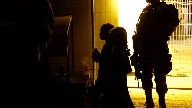 This handout picture released by the Israeli Army on July 22, 2017, shows an Israeli soldier standing guard near a family member of the Syrian White Helmet rescuers at an unknown location. PHOTO: AFP