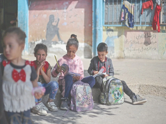 palestinian children sit with their schoolbooks at a school in the nuseirat refugee camp in the central gaza strip photo afp palestinian children sit with their schoolbooks at a school in the nuseirat refugee camp in the central gaza strip photo afp