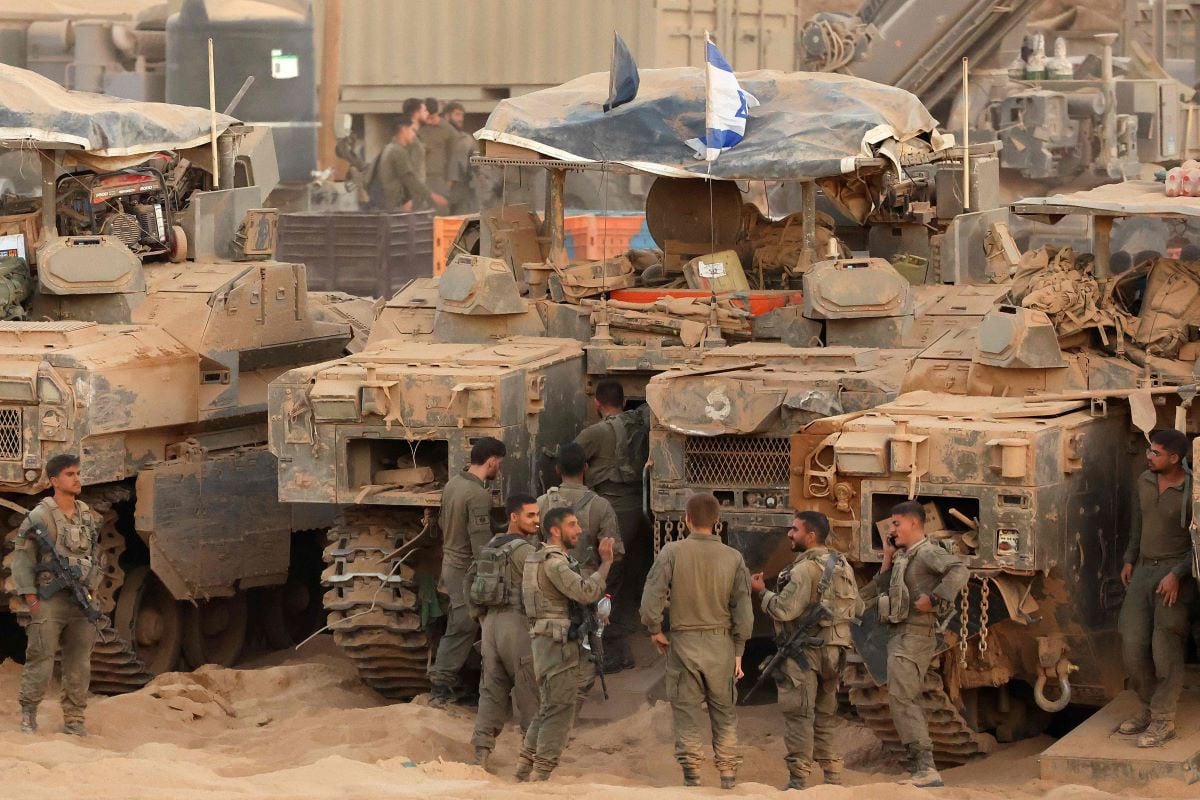 Israeli army soldiers gather near infantry-fighting vehicles (IFVs) at a position along the Israel-Gaza border fence on October 10, 2025. Gaza's civil defence agency said October 10 that Israeli forces have begun pulling back from parts of the territory, particularly in Gaza City and Khan Yunis. PHOTO: AFP